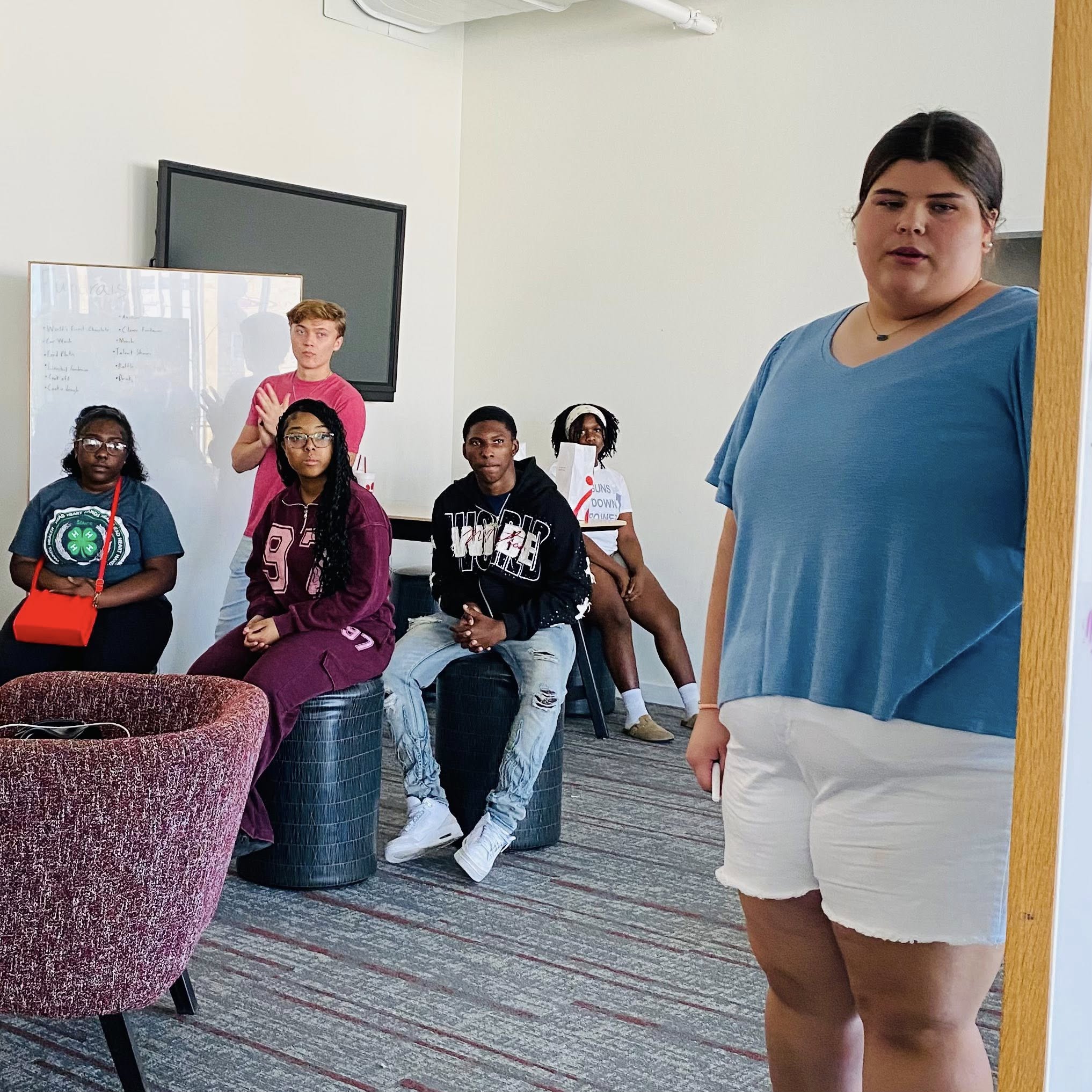 Six teenagers looking toward an open doorway.